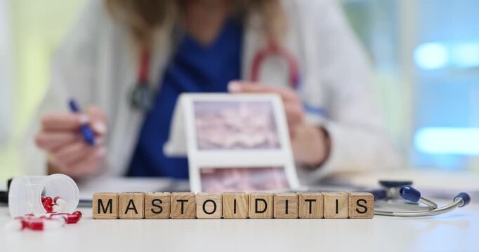 Wooden cubes form word Mastoiditis highlighting ear infection problem. Medical pills and diagram on desk create focus on disease explanation