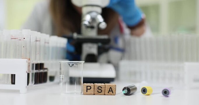 Wooden cubes spell PSA drawing attention to prostate test abbreviation at glassware. Laboratory tubes stand around showing blood screening process