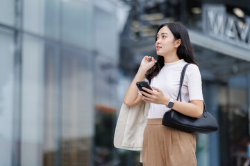Businesswoman using smartphone and holding jacket in urban setting
