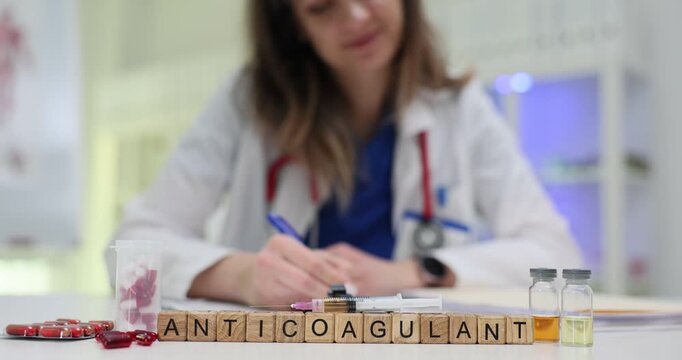 Wooden cubes spell Anticoagulant focusing on blood thinning medicine concept. Lab desk shows medical vials and paperwork creating research mood