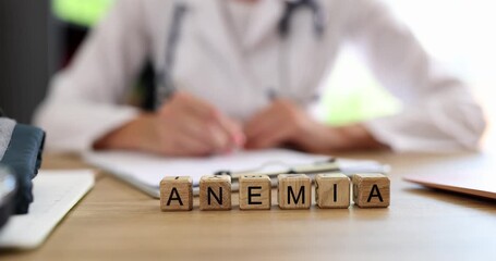 Wooden cubes form word Anemia near woman in medical coat writing patient history. Word brings sense of health concern creating serious hospital vibe - Powered by Adobe