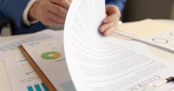 Man looks through points on contract with pen sitting at desk. Pen moves along document creating signs of disagreement. Businessman signs contract