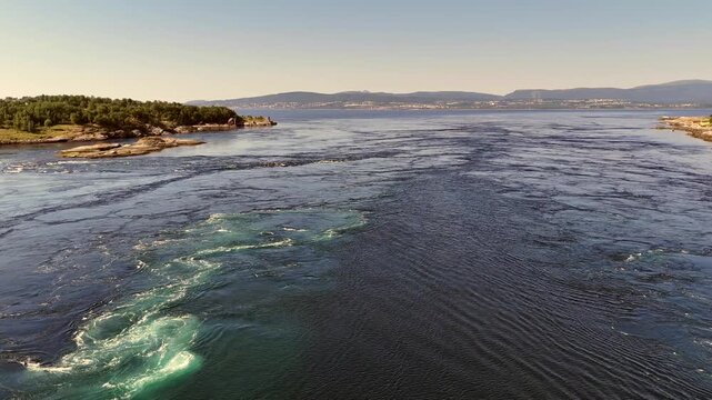 drone flying low over the Saltstraumen tidal current at sunrise with distant hills near Bodoe
