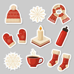 Set of Scandinavian-style winter stickers on light background featuring hat, scarf, snowflakes, socks, mittens, thermos, and coffee cup, cozy festive design for seasonal projects.