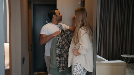 A man takes shirts out of the closet and consults with a pregnant woman next to him - Powered by Adobe