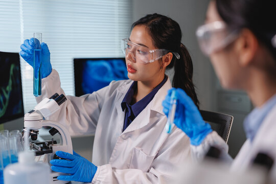 Scientists analyzing blue chemical liquid in test tube in laboratory