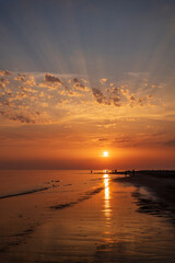 sunset on the beach with clouds and sun rays