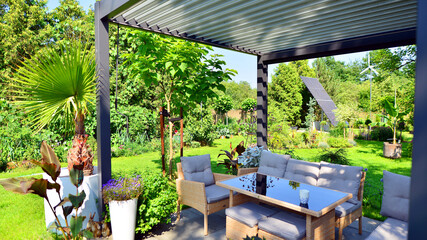 Fototapeta premium Modern aluminum pergola with stylish garden furniture in a beautiful garden.