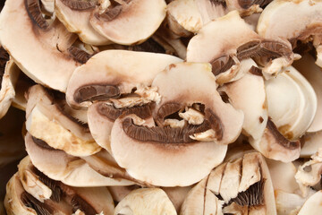 A full-frame close-up shot of a large pile of freshly sliced mushrooms, ready for cooking