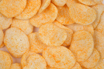 A close-up of a pile of crunchy oval wheat and oat snacks sprinkled with orange powder