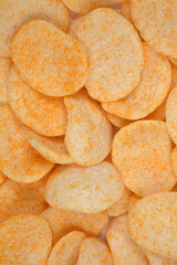 A close-up of a pile of crunchy oval wheat and oat snacks sprinkled with orange powder