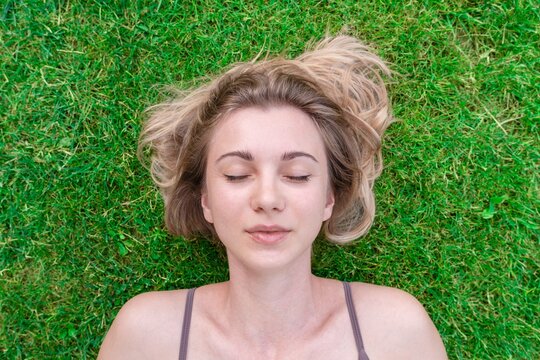 Close up of beautiful young woman lying down in the green grass