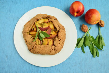Nectarine galette with sage and honey on blue background
