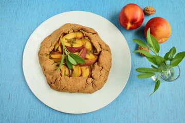 Nectarine galette with sage and honey on blue background