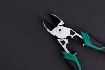 Wire cutter pliers with green handles on dark background