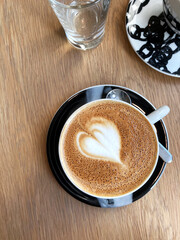 Freshly Made Flat White Coffee with Heart Latte Art on Wooden Cafe Table.