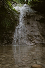 waterfall  in the forest leading into the Bregenzer Ache  in Vorarlberg Austria in brown colours 
