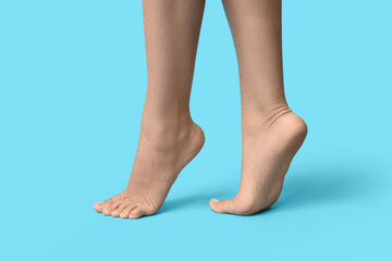 Legs of young woman with pedicure on blue background