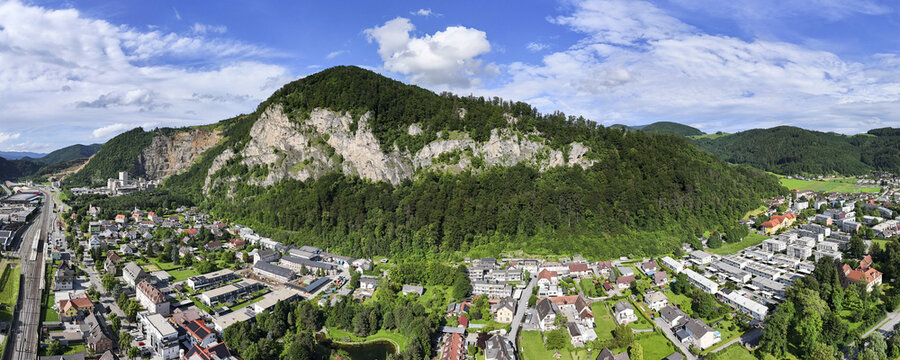 Aerial panoramic view of Peggau and the Peggauer Wand, the contrasting textures of rock and forest converge above the town, Peggau-Deutschfeistritz, Styria, Austria.