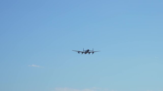 Warplane Avro Lancaster approaching in clear sky historical museum bomber from World War Two. Classic four engine aircraft gliding forward heritage combat plane from WWII. Iconic vintage bomber