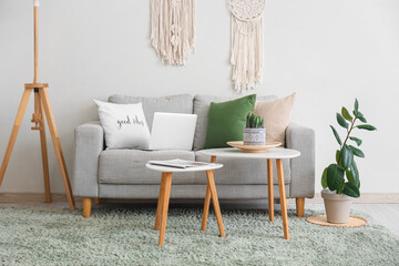 Interior of stylish living room with grey sofa, coffee table and standard lamp near white wall