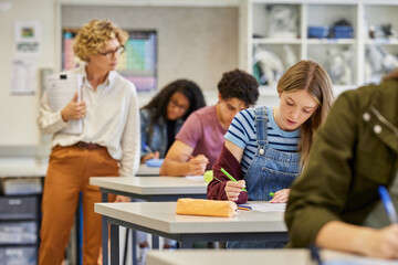 Female teacher observes students during exam at high school