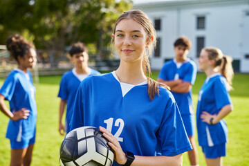 Portrait of focused soccer female player holding football ball
