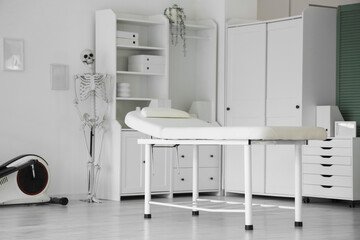 Interior of physiotherapist's office with couch, shelf unit and human skeleton model