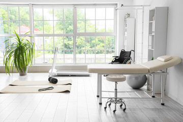 Interior of physiotherapist's office with sports equipment, couch and wheelchair