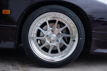 Close-up detail of beautiful two-piece, multi-spoke alloy wheels with bolts and sport tires, showcasing a classic JDM tuning style