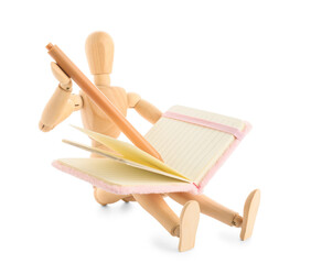 Wooden mannequin with notebook and pen sitting on white background