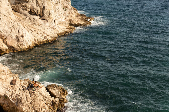 Vue plongeante sur les rochers blancs et la mer M&eacute;diterran&eacute;e &agrave; Marseille, deux jeunes femmes en maillot de bain assises au soleil sur les rochers, ville de Marseille, Sud de la France

