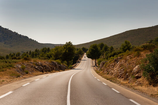 Panorama sur une route de montagne dans le sud de la France au coucher du soleil avec une ambiance lumineuse chaude, moto vue de face au loin, Marseille