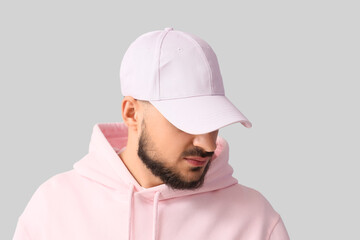 Handsome young man in stylish cap on grey background