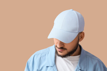 Handsome young man in stylish cap on beige background