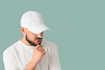 Handsome young man in stylish cap on blue background