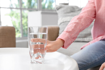 Cute little boy taking glass of water in living room