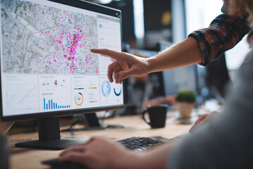 Close-up of mentor’s hands guiding junior employee through AI dashboard.