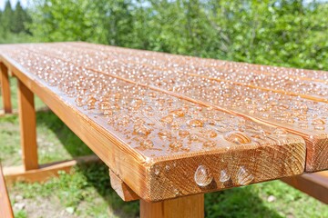 Close-up of a wooden picnic table with water droplets on the surface
