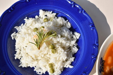 Boiled white rice with green peas in a blue plate