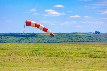 Red and white windsock on clear day at open field