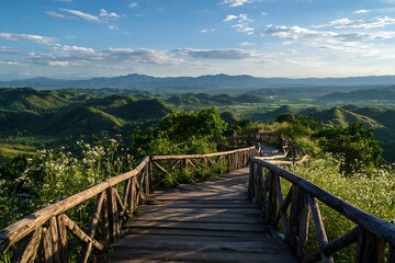 Fototapeta premium Wooden walkway leads to a scenic vista of rolling green hills under a blue sky