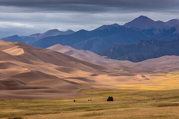 Obraz premium Vast sand dunes meet a mountain range under a dramatic sky