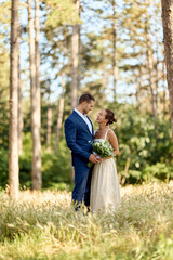 Fototapeta premium Bride and Groom Smiling in a Forest Meadow, Romantic Outdoor Wedding Portrait
