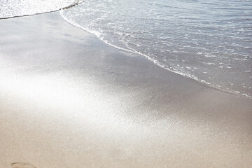 Ocean water on beach sea sand with sun reflection