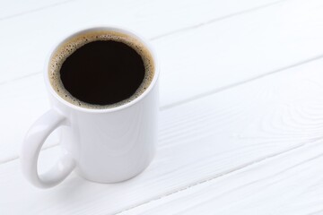 Aromatic coffee in cup on white wooden table, closeup. Space for text