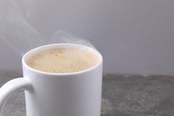 Aromatic coffee in cup on grey textured table, closeup. Space for text