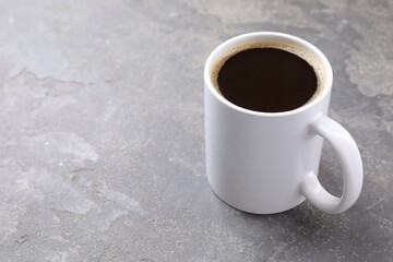 Aromatic coffee in cup on grey textured table, closeup. Space for text
