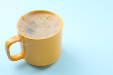 Aromatic coffee in cup on light blue background, closeup. Space for text
