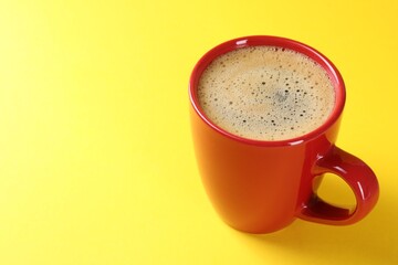 Aromatic coffee in cup on yellow background, closeup. Space for text